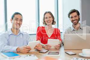 Smiling business executives using laptop and digital tablet in conference room