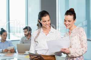 Two female business executives discussing over document in conference room