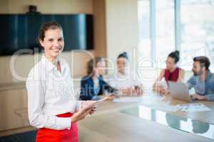 Portrait of smiling female business executive standing in conference room with digital tablet