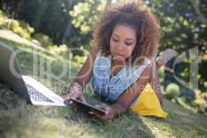 Woman lying on grass and using digital tablet