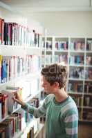 Schoolboy selecting book in library