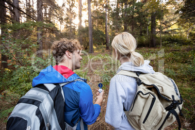 Rear view of hiking couple holding a compass and pointing forward