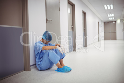 Sad surgeon sitting on floor in corridor