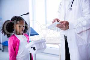 Doctor using digital tablet while measuring height of girl