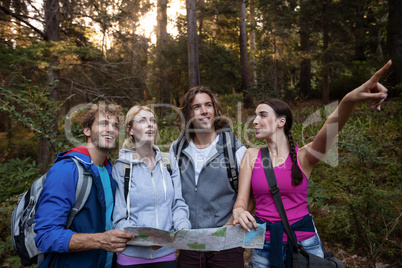 Group of friends holding a map and looking forward while hiking