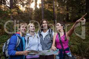 Group of friends holding a map and looking forward while hiking