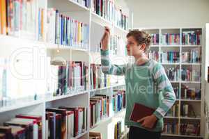 Schoolboy selecting book in library