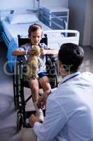 Male doctor interacting with child patient in ward