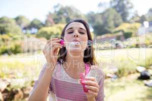 Woman blowing bubbles in park