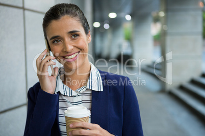 Business executive talking on mobile phone while having coffee