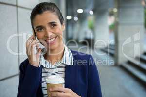 Business executive talking on mobile phone while having coffee