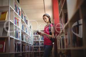 Portrait of schoolgirl using digital tablet in library