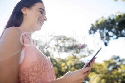 Smiling woman using a digital tablet in the park