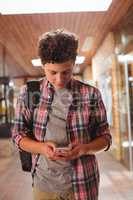 Schoolboy using mobile phone in corridor at school