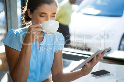 Female executive using digital tablet while having coffee