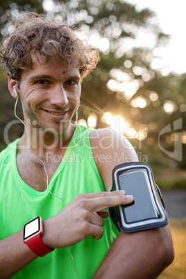 Smiling jogger listening to music from mobile phone