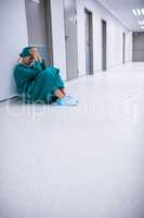 Tensed female surgeon sitting in corridor