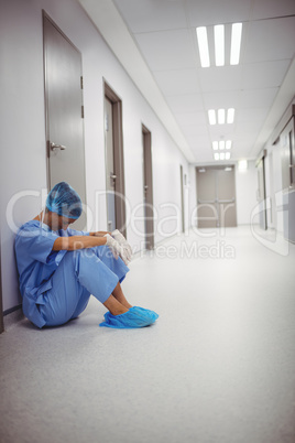 Sad surgeon sitting on floor in corridor