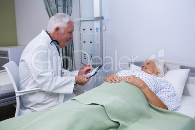 Doctor discussing report with senior patient in ward