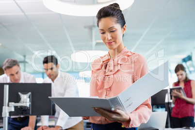 Business executive holding clipboard at desk in office