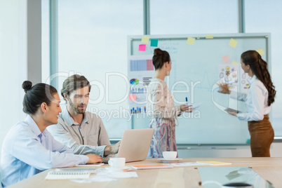 Business executives discussing over laptop in conference room