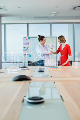 Smiling business colleagues shaking hands in conference room