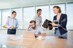 Colleagues with document, digital tablet and mobile phone talking to frustrated man