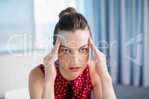 Tense female business executive sitting with hand on forehead