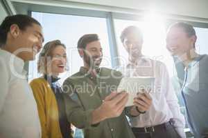 Smiling business executives discussing over digital tablet