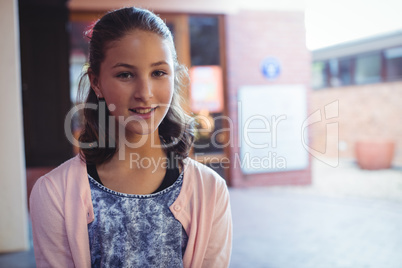 Happy schoolgirl sitting in school campus