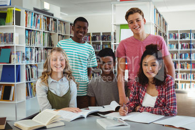 Portrait of happy classmates studying in library