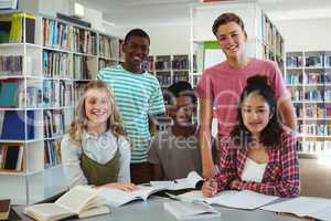 Portrait of happy classmates studying in library