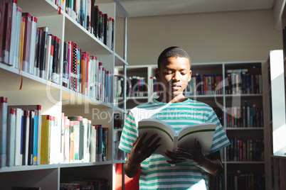 Attentive schoolboy reading book in library