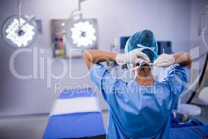 Female nurse tying surgical mask in operation theater