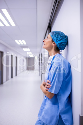 Sad surgeon leaning on wall in corridor