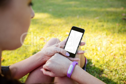 Woman with fitness band on her wrist using her mobile phone