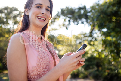 Portrait of smiling woman using her mobile phone in the park