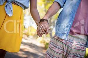 Mid section of couple holding hands in park