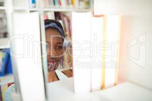 Schoolgirl selecting book from book shelf in library