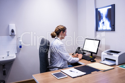 Attentive doctor working on computer in clinic