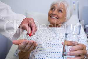 Doctor giving medicine pill to senior patient
