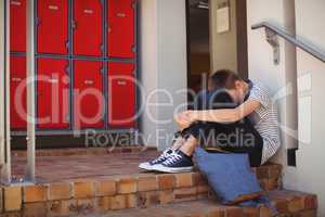 Sad schoolboy sitting on staircase