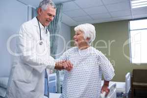 Doctor assisting senior patient in ward