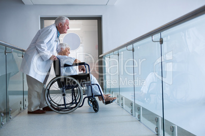 Doctor and senior patient on wheelchair in the passageway