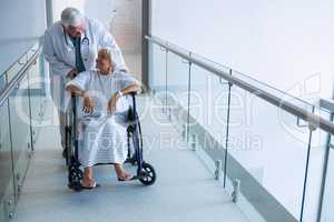 Doctor holding senior patient on wheelchair in passageway