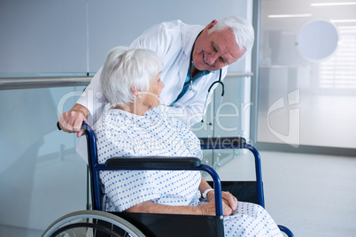 Doctor holding senior patient on wheelchair in passageway