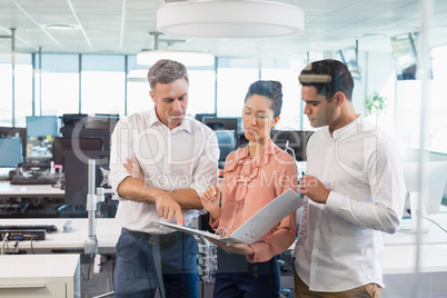 Business colleagues discussing over clipboard at desk