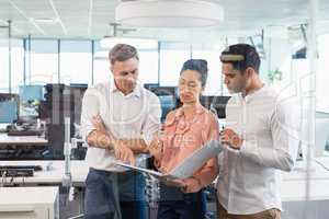 Business colleagues discussing over clipboard at desk