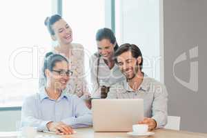 Business executives discussing over laptop in conference room