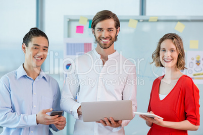 Smiling business colleagues using mobile phone, digital tablet and laptop